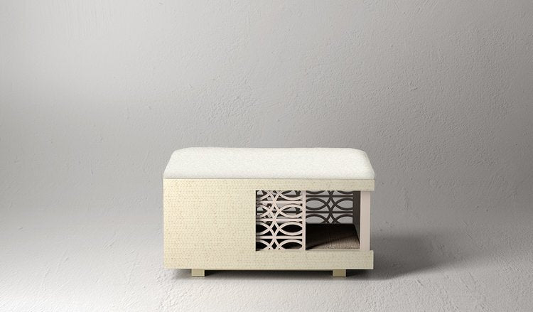 A cream-colored ottoman in a mid-century design with a white Prima Alpaca top cushion.  The left one-third is enclosed and the right two-thirds is open revealing a completely finished interior behind a tonal sliding door screen in an open modern wave design.  The cream colored wood finish appears solid from a distance, but is actually a lovely Italian white snakewood pattern.